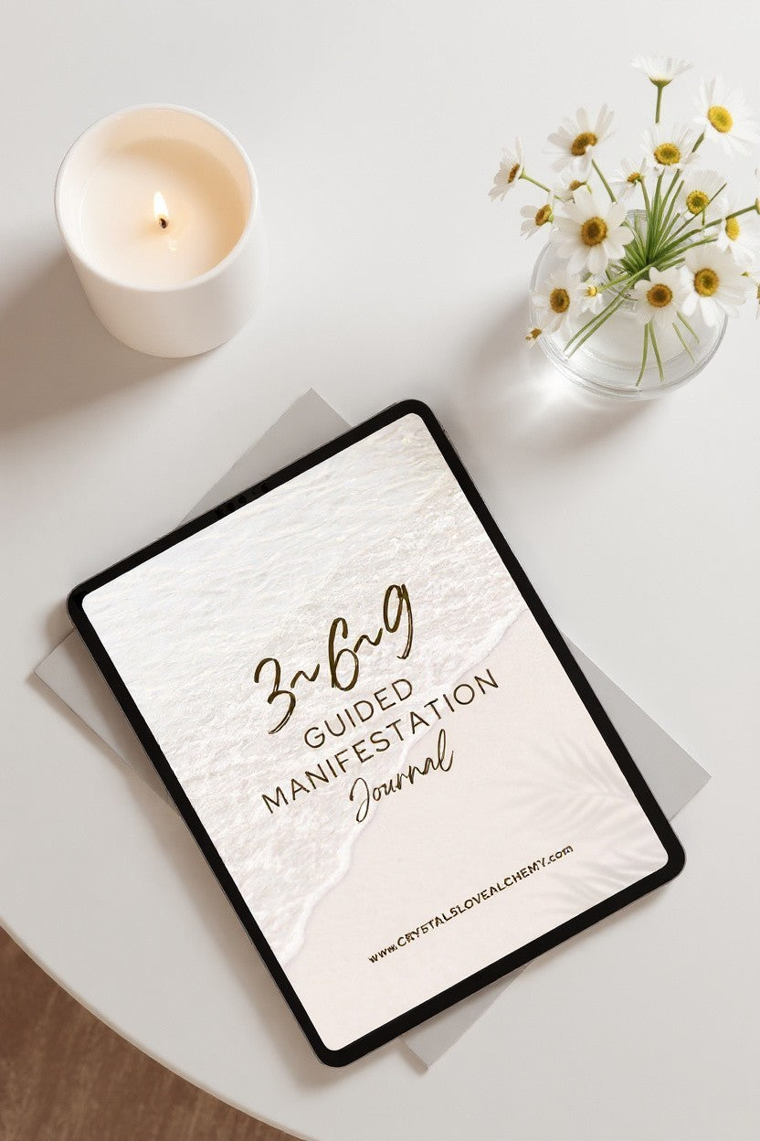 369 Guided Manifestation Journal displayed on a white table with a candle and flowers.