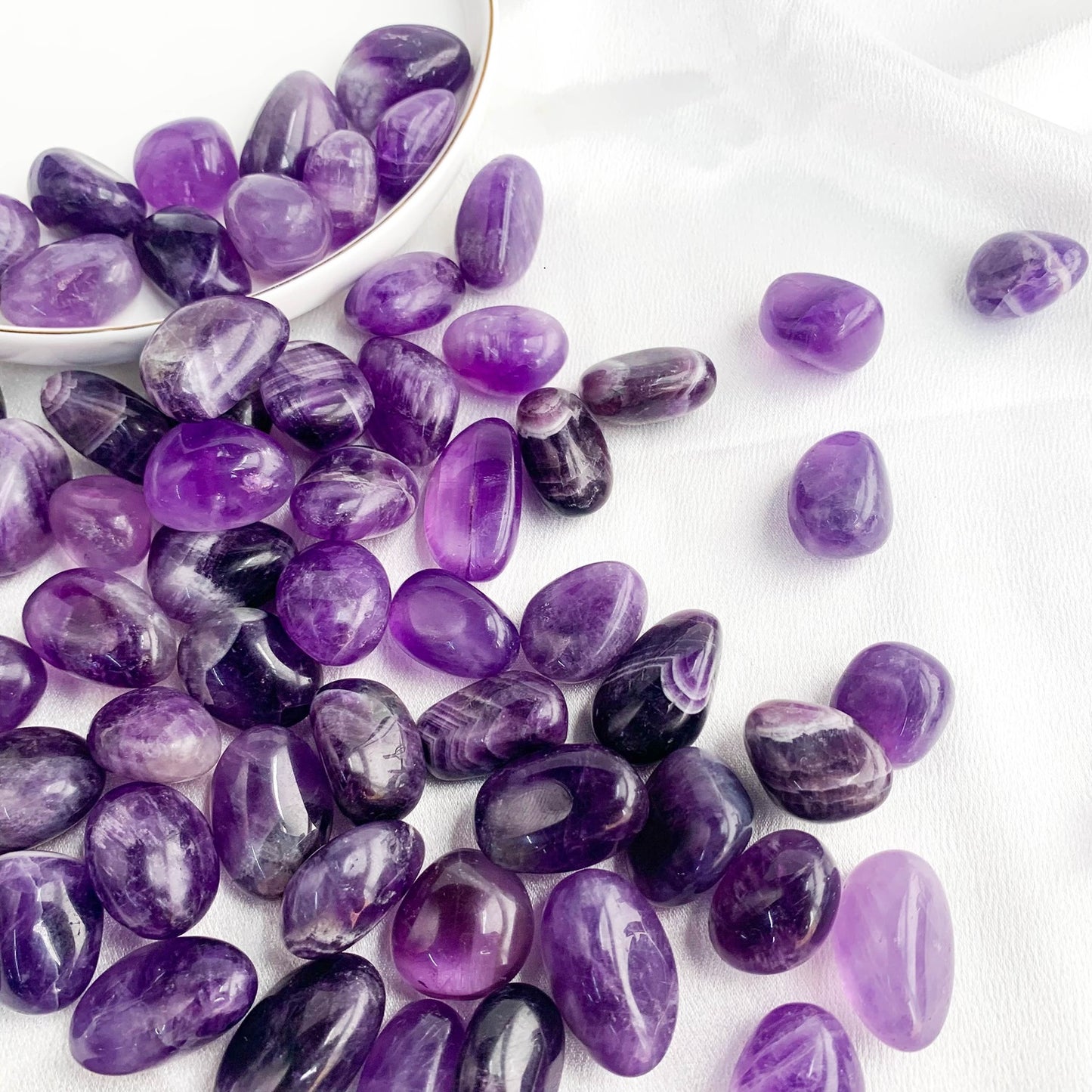 Amethyst pocket gems scattered on a white surface, showcasing their calming purple hues and smooth textures.