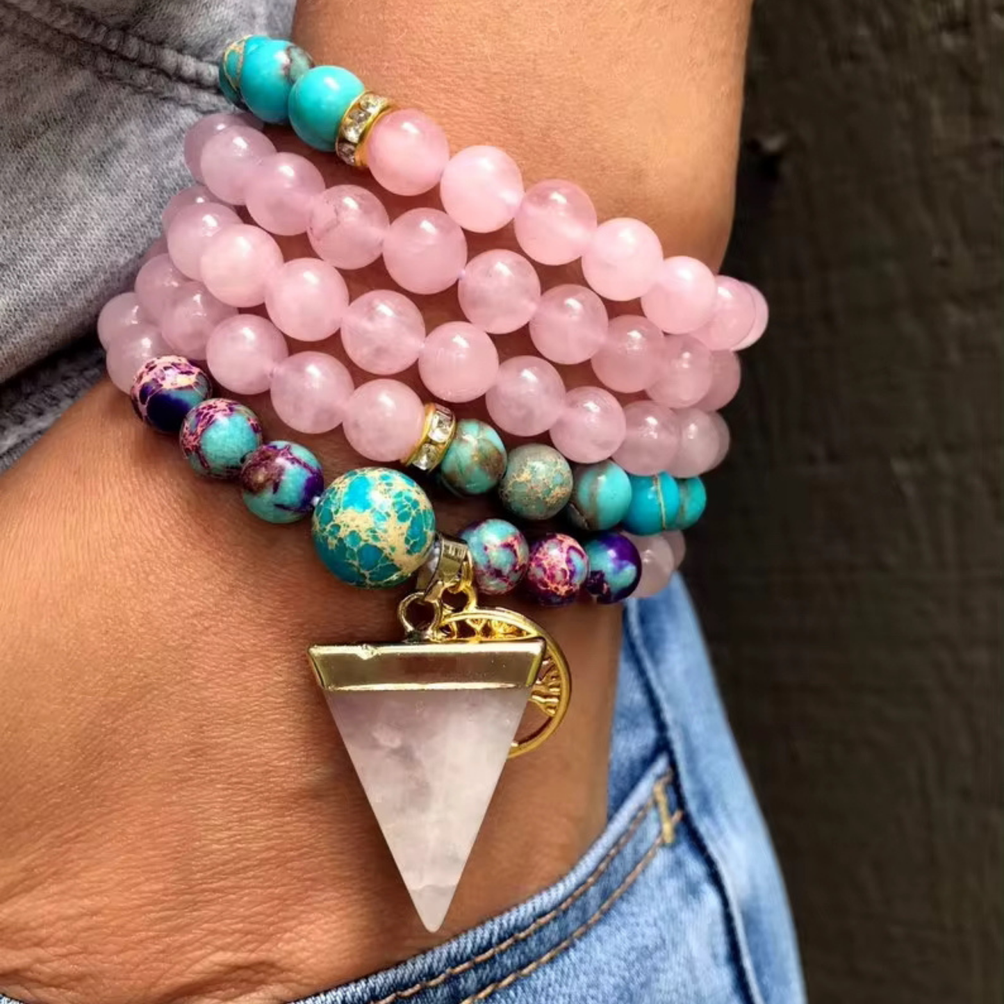 Handcrafted Rose Quartz & Jasper mala bracelet with gold and gemstone accents, worn on a hand.