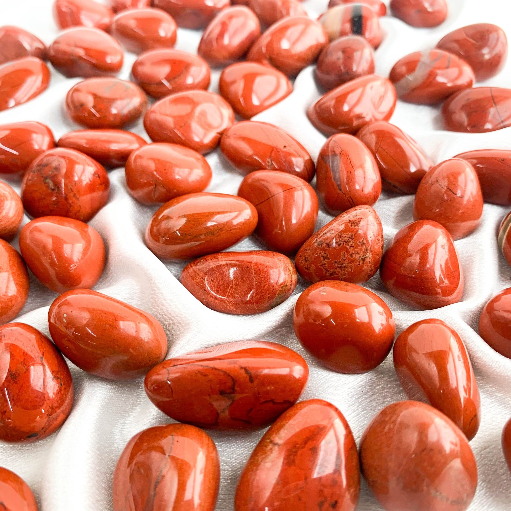 Red Agate Pocket Gems on soft fabric, showcasing their vibrant color and polished texture for grounding and strength.